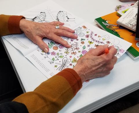 Close up of an adult coloring a picture of flowers