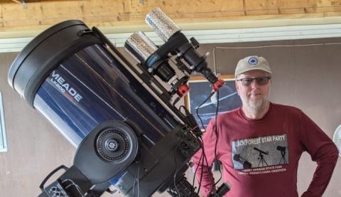 Man standing next to a telescope