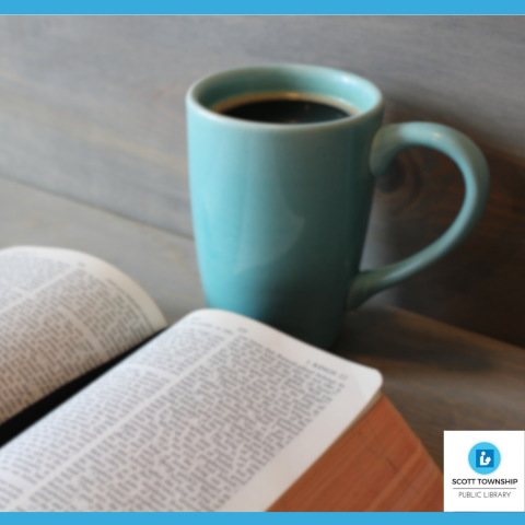 A blue mug with coffee next to an open book.